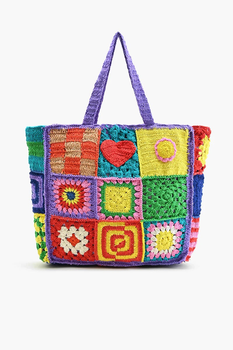 A multicolored crochet tote bag with a playful, patchwork design featuring various geometric and heart-shaped patterns.
