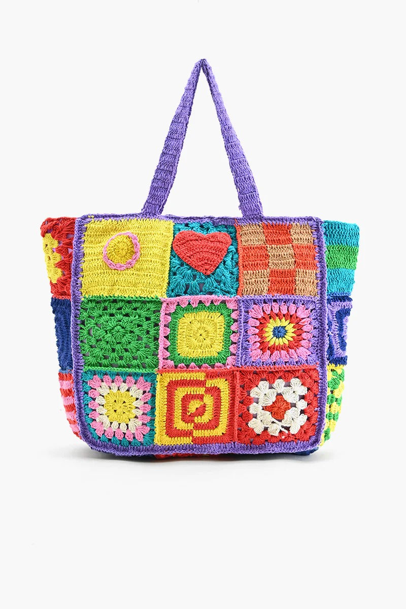A multicolored crochet tote bag with a playful, patchwork design featuring various geometric and heart-shaped patterns.