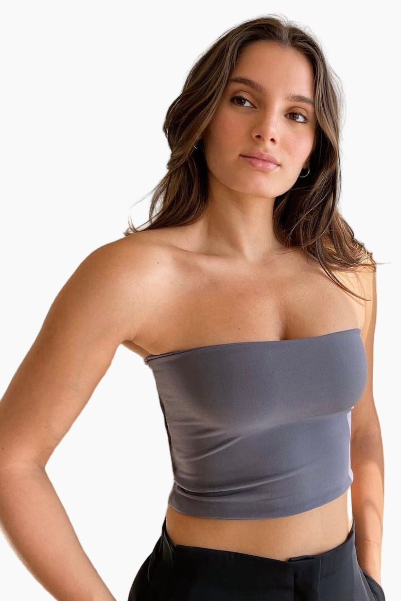 Woman wearing a strapless gray top against a white background