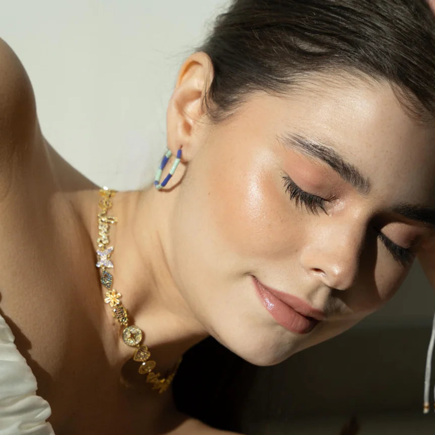 Close-up of a woman wearing gold jewelry with a neutral background