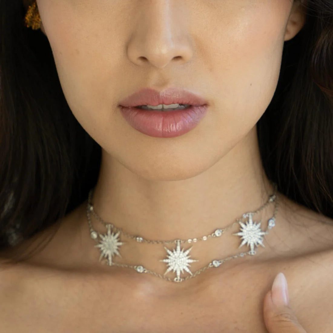 Close-up of a woman wearing a star-shaped necklace with a neutral background