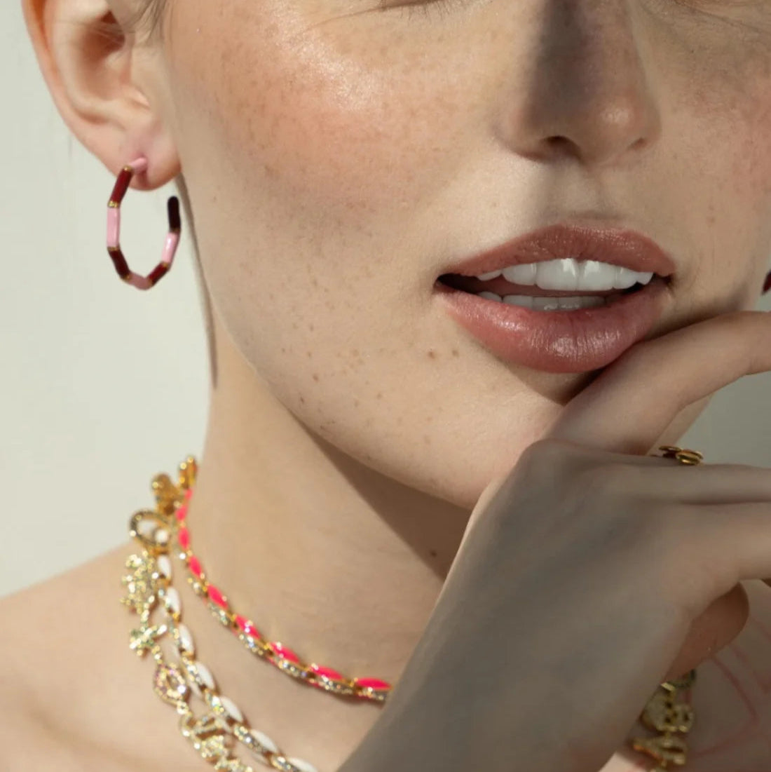 Close-up of a person wearing gold jewelry with a neutral background