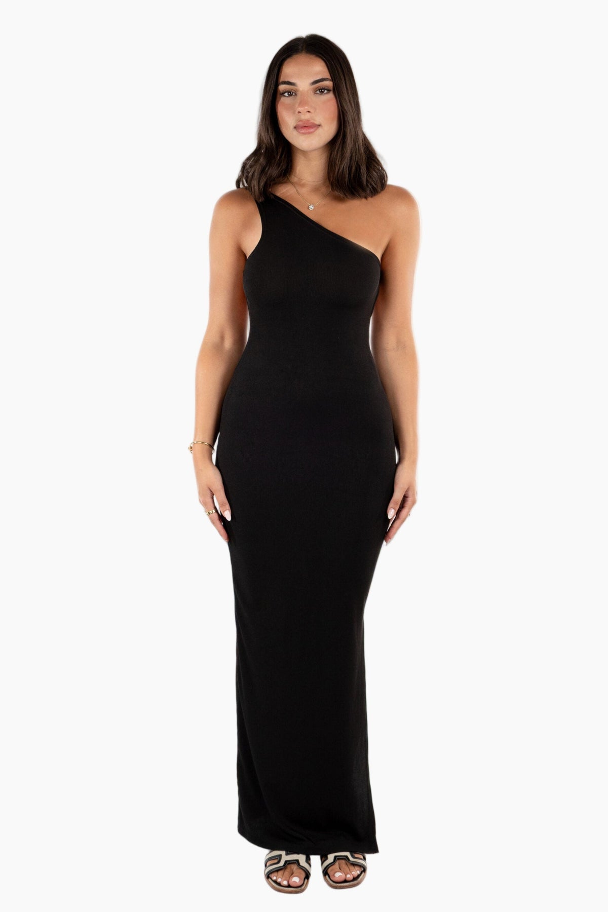 Woman wearing a black one-shoulder dress. Softly structured in a ribbed knit, this maxi dress is cut with a clean open back for a subtle reveal. Streamlined, easy, and designed to hold its shape.