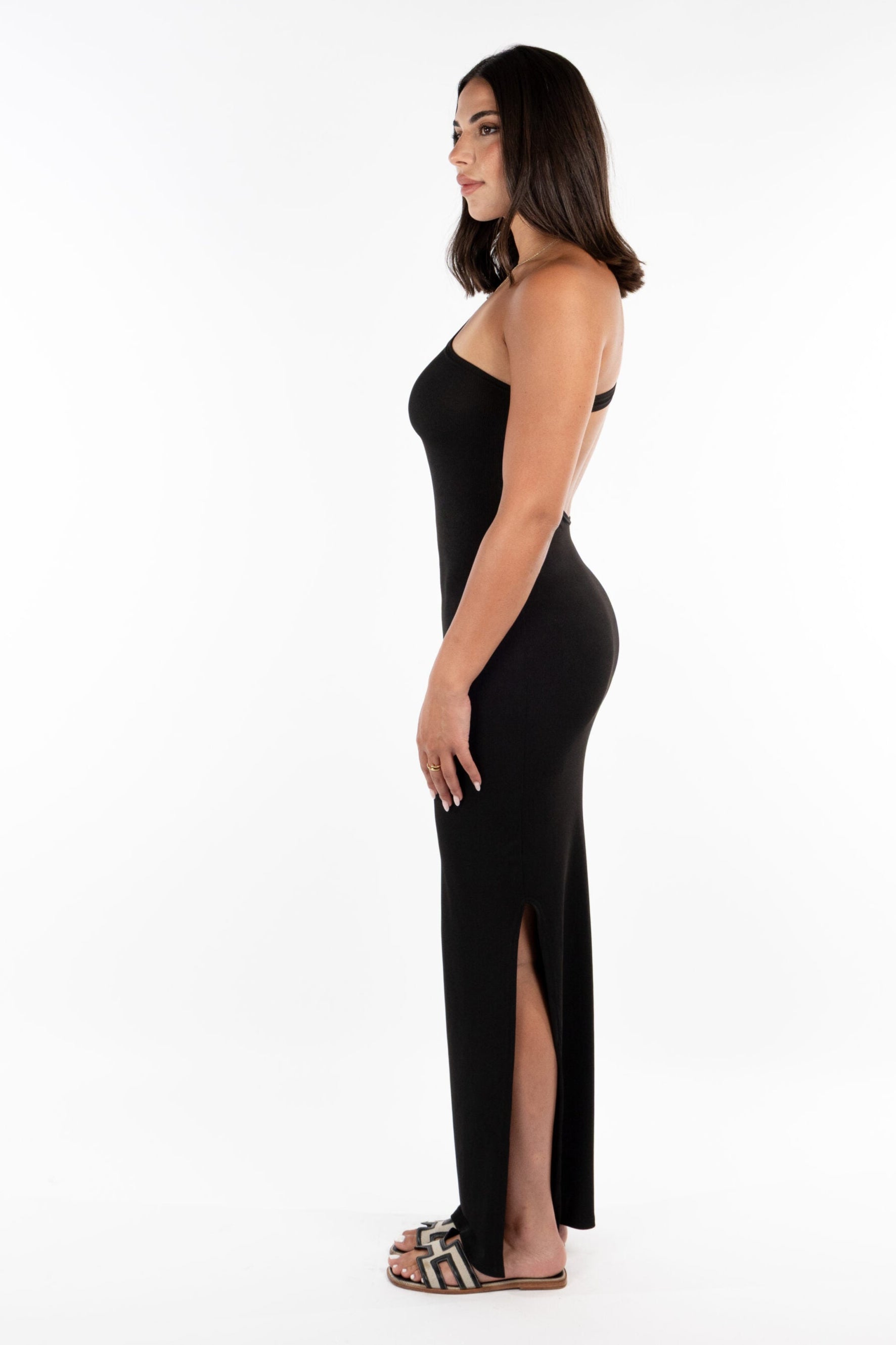 Woman wearing a black dress with a slit on a white background