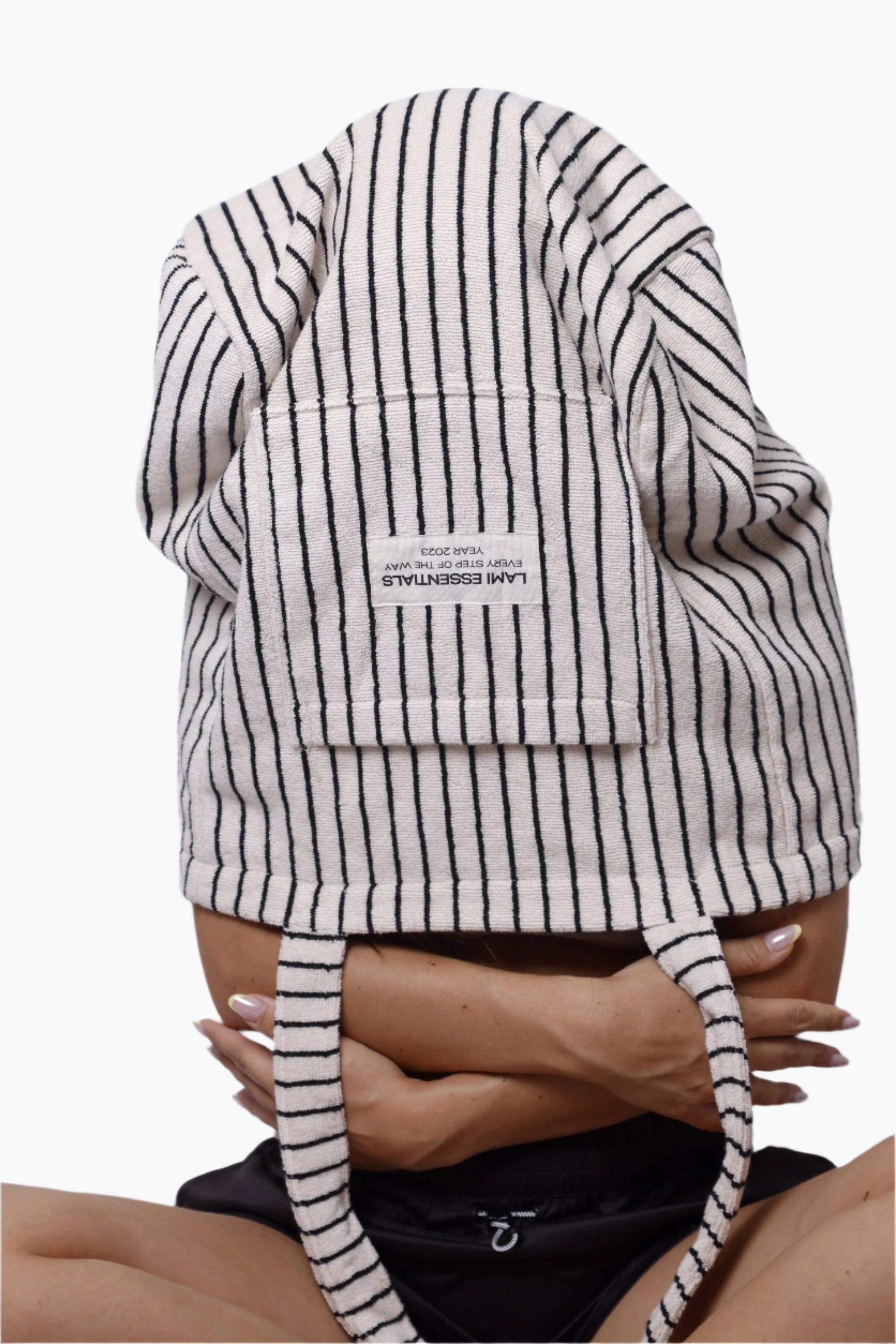 Person wearing a black and white striped garment with a visible brand label " lami essentials"