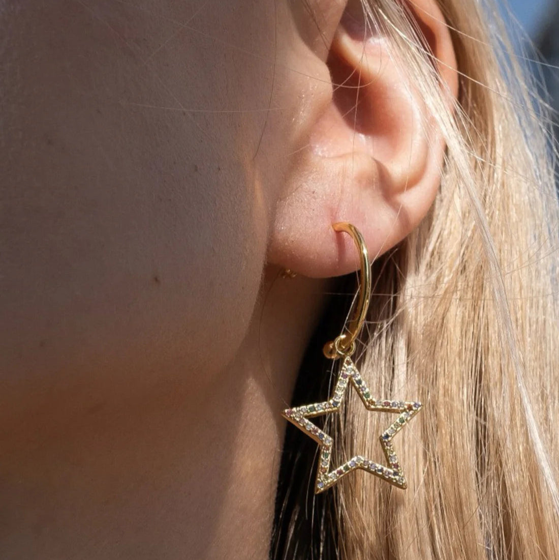 Close-up of a person wearing a gold star-shaped earring.