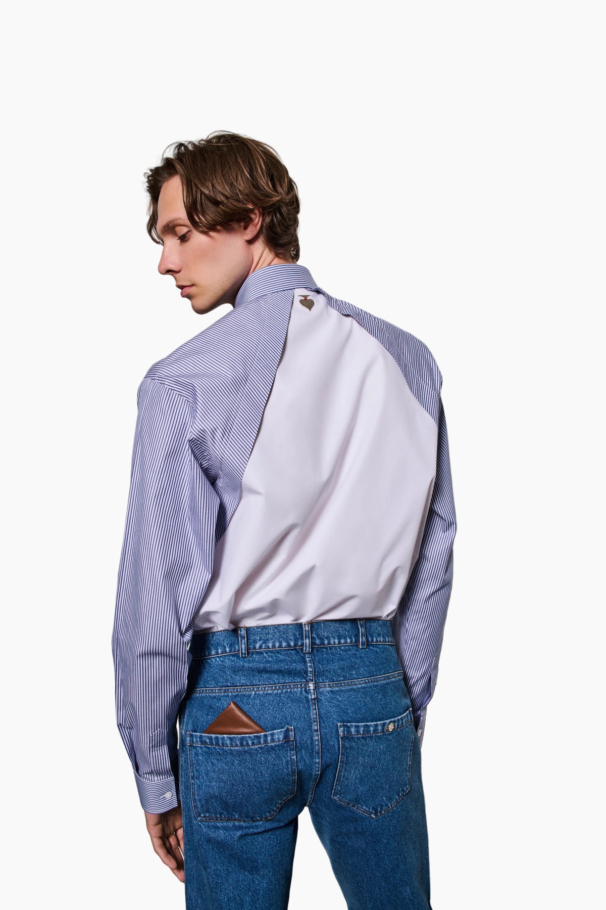 Person wearing a two-tone shirt with blue and white sleeves against a plain background