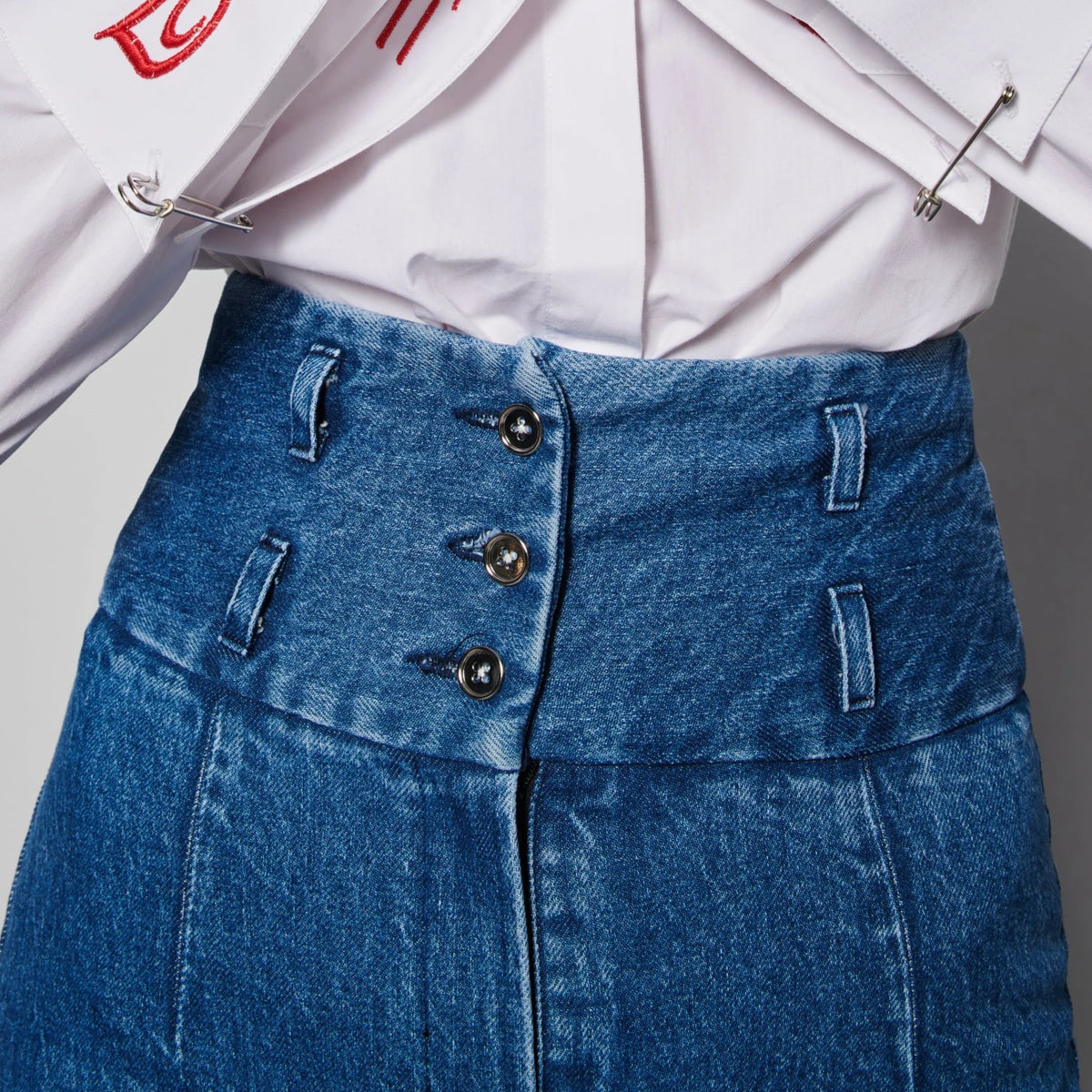 High waist boot cut indigo jeans fit to waist with stretch cotton fabric, detailed with three front buttons and two belt loops.