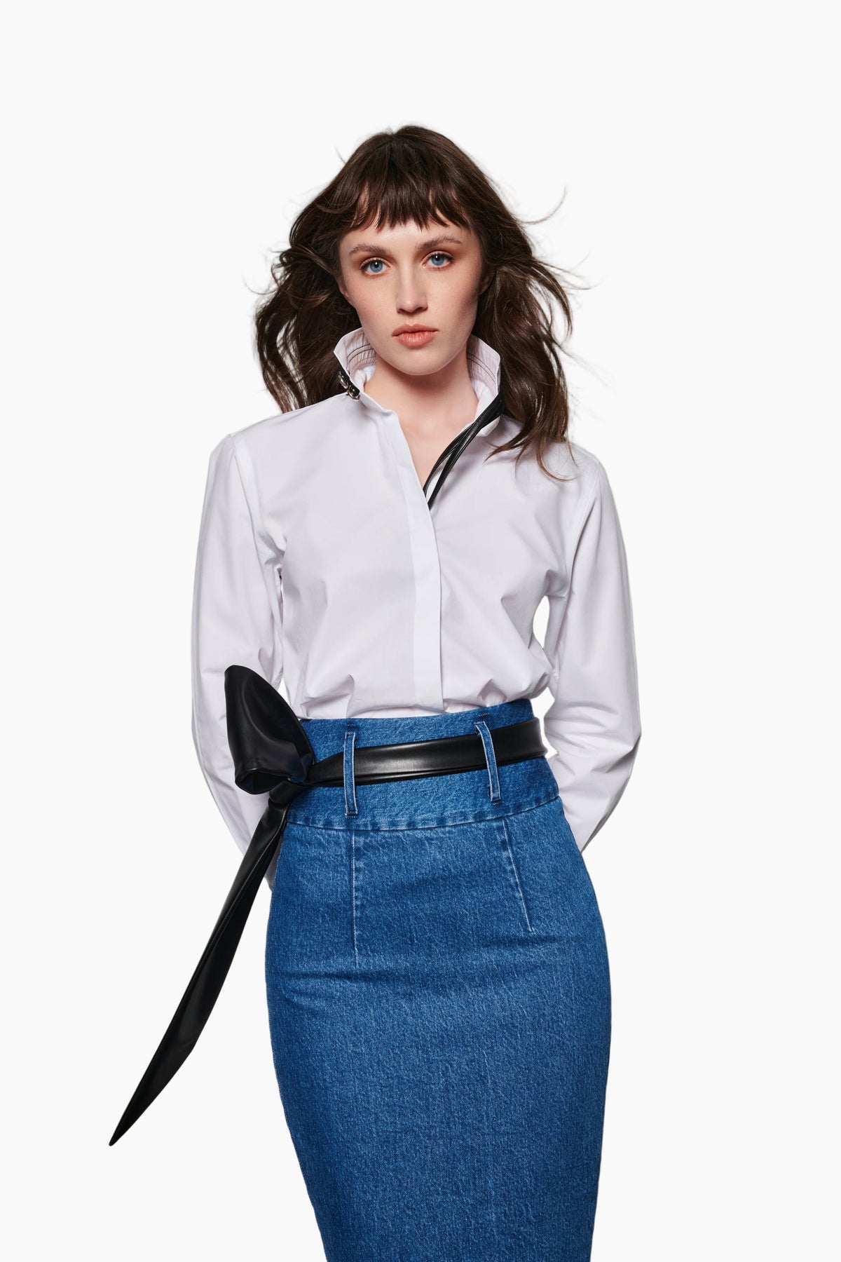 Woman wearing a white blouse with a high waist indigo jeans fit to waist skirt with stretch cotton fabric, detailed with two belt loops.