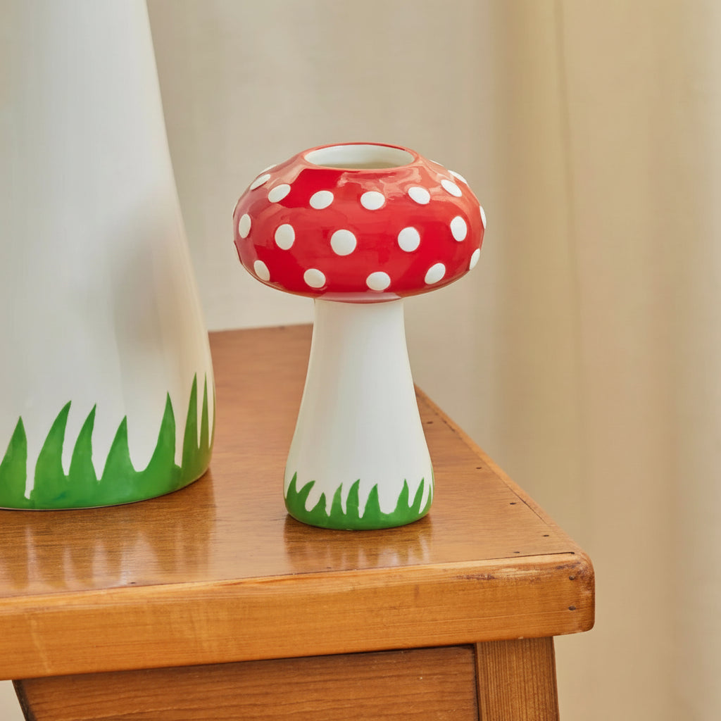 Mushroom-shaped vase with red polka dot cap on a wooden surface