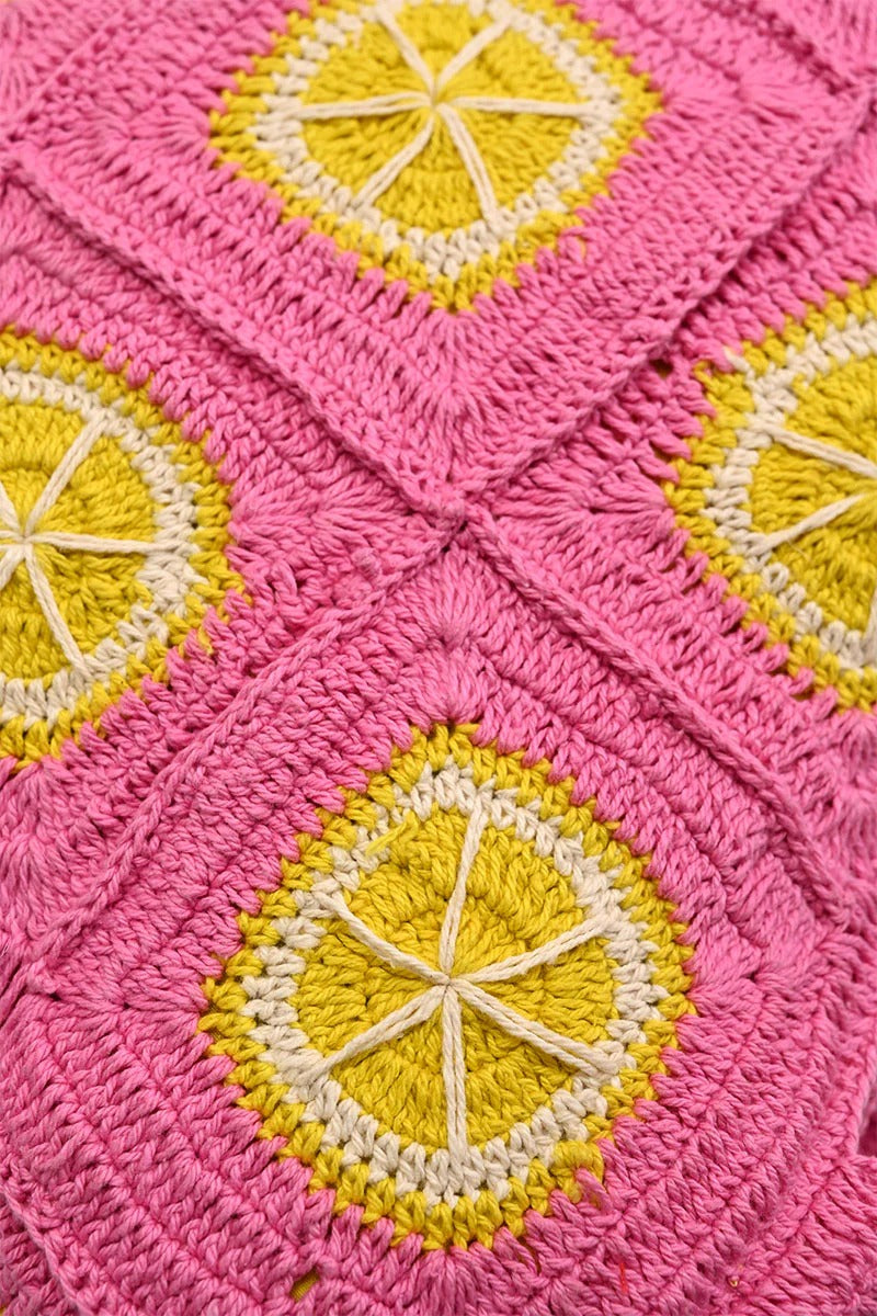 A vibrant pink and yellow crochet beach tote with metallic button closure and double shoulder straps.