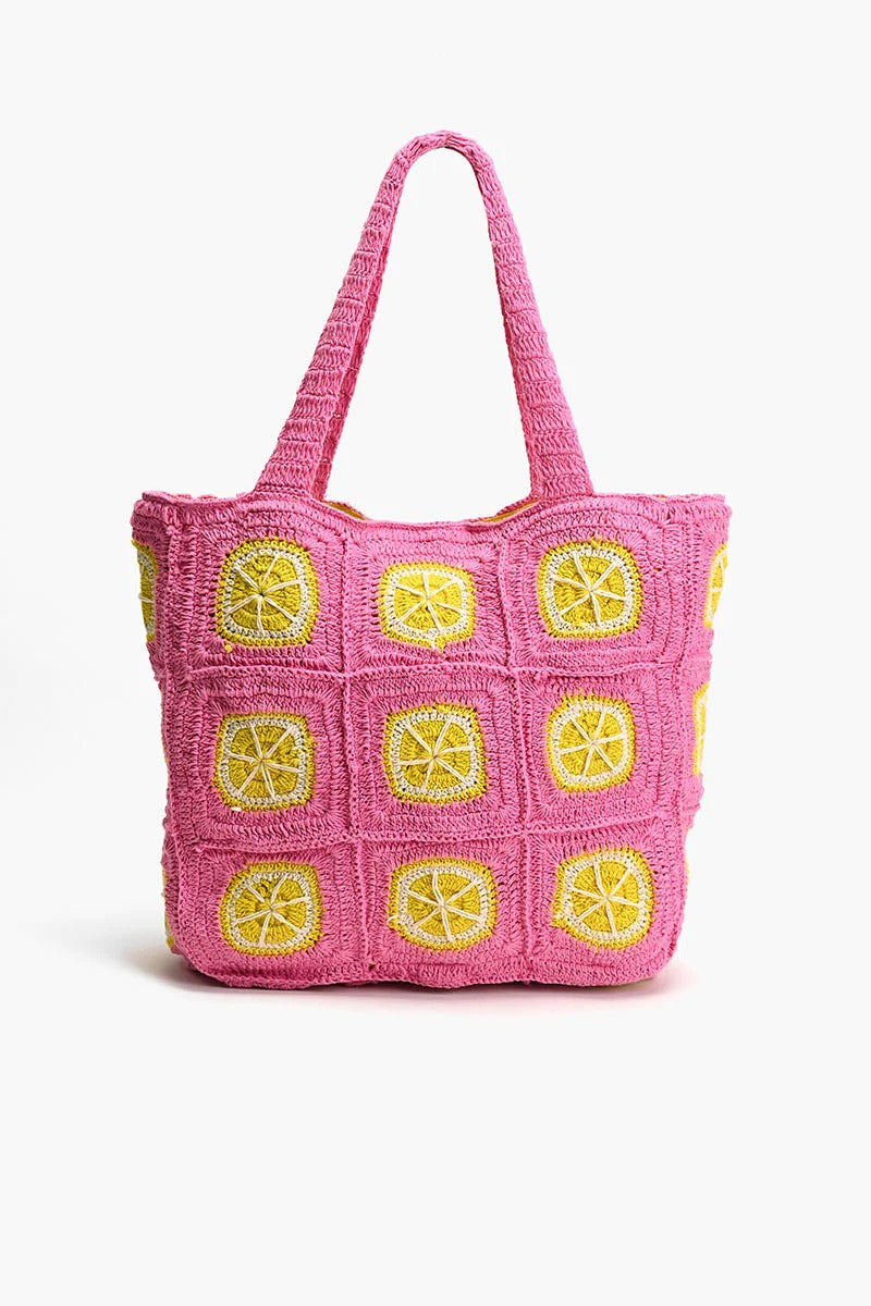 A vibrant pink and yellow crochet beach tote with metallic button closure and double shoulder straps.