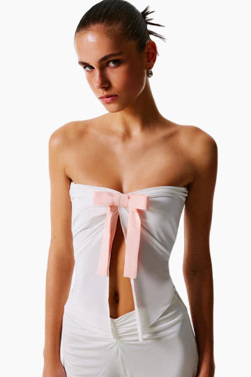 Woman wearing a white strapless dress with a pink bow
