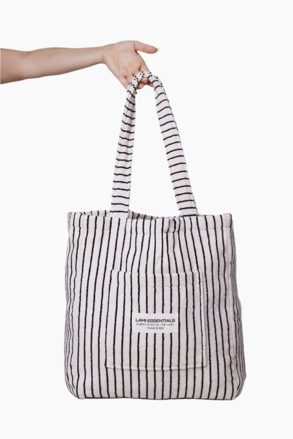 Striped tote bag with a visible brand label held by a hand against a white background