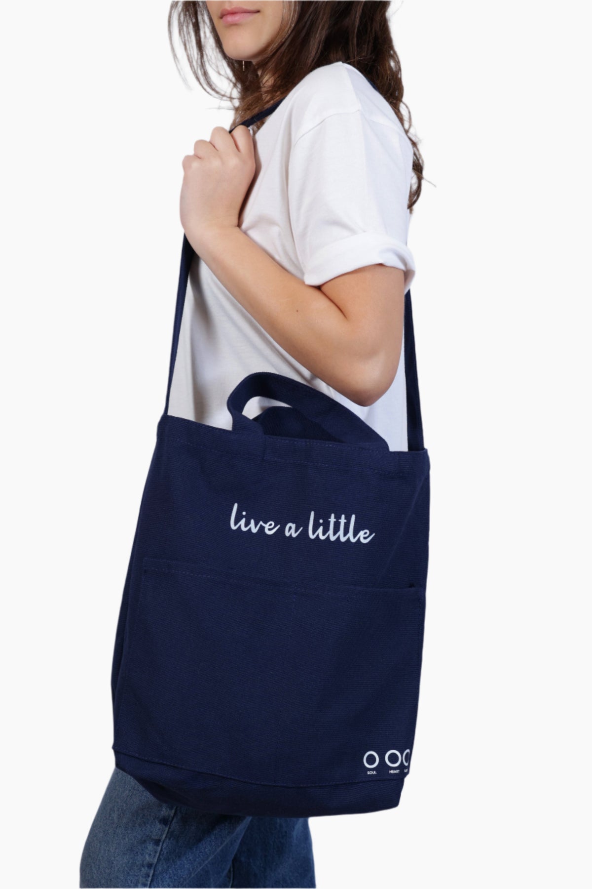 Person holding a navy blue tote bag with 'live a little' text