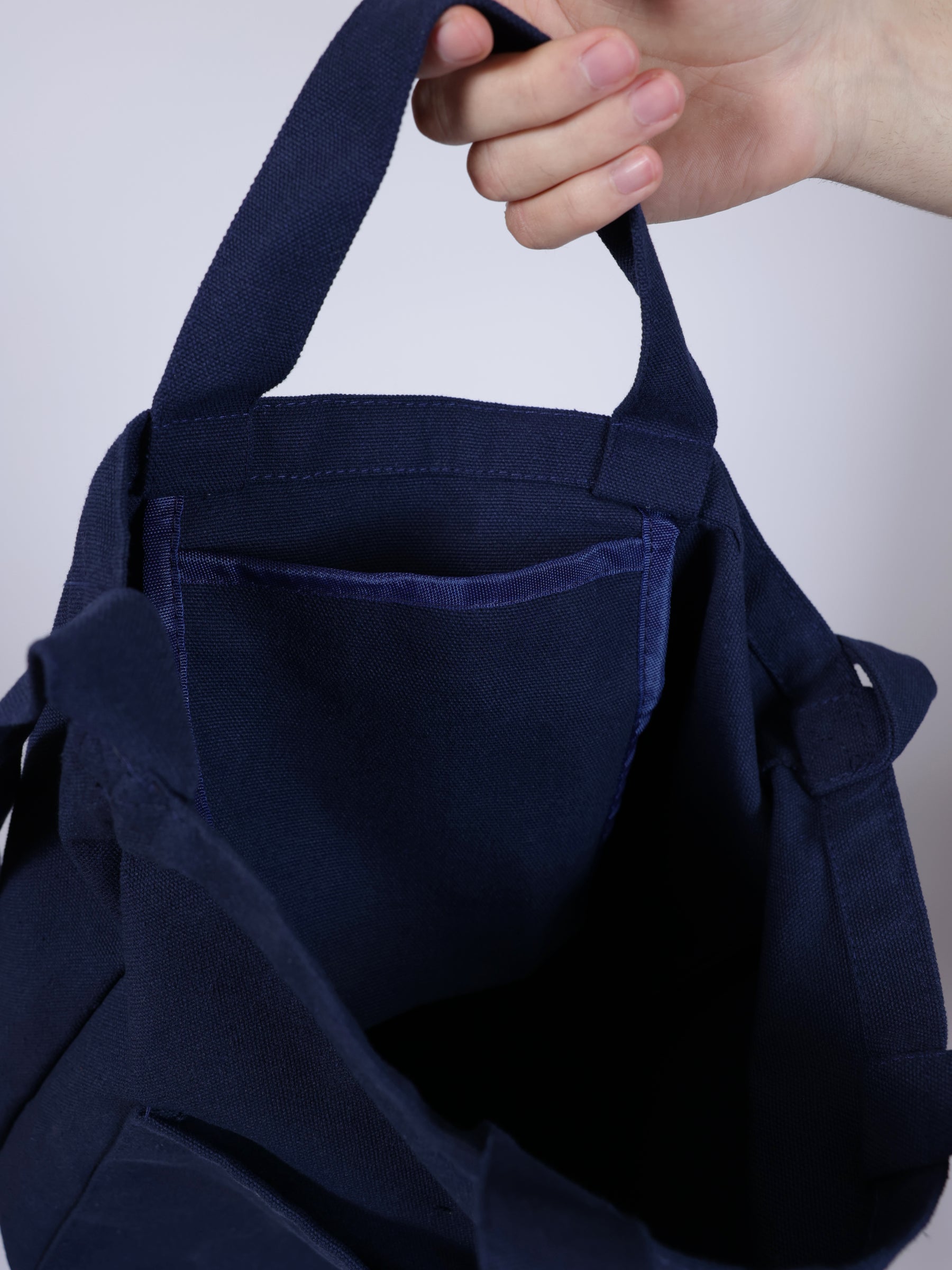 Person holding a navy blue tote bag