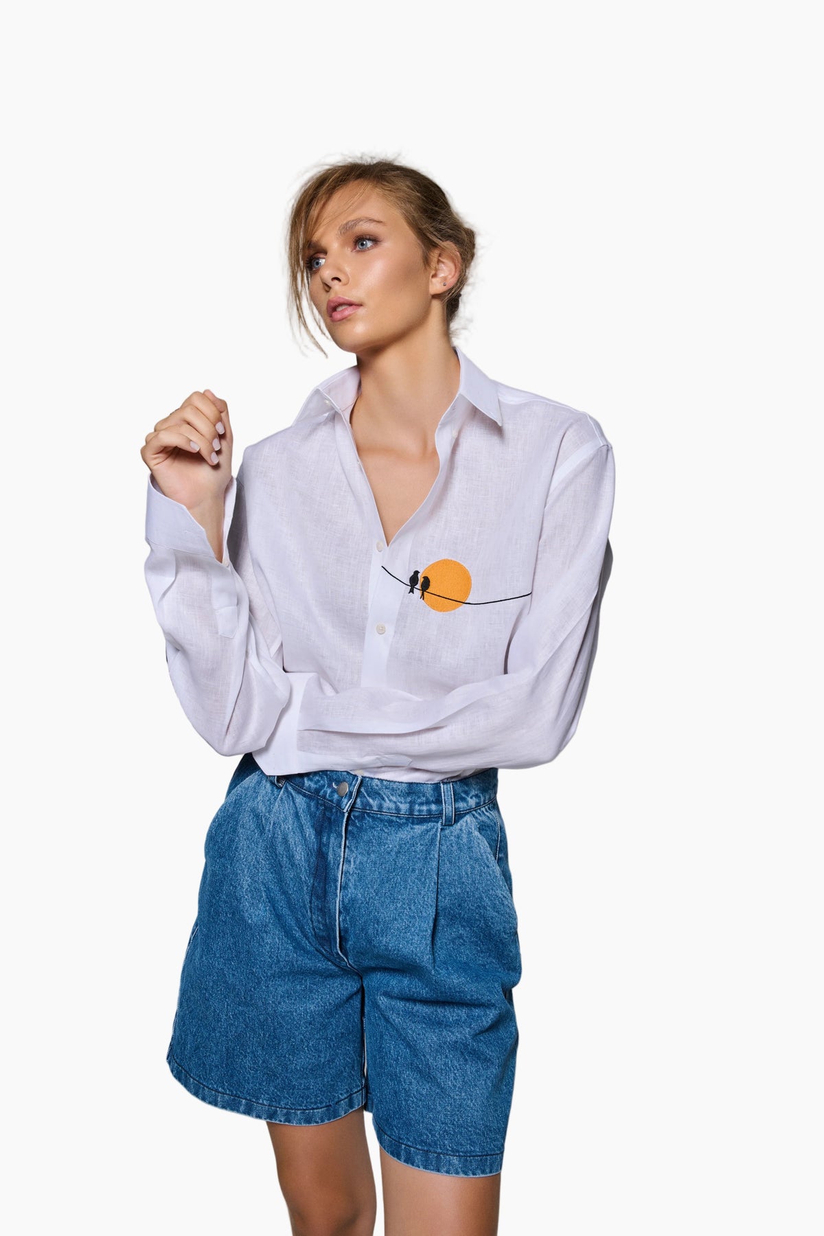 Woman wearing a white shirt with a small orange detail and blue shorts