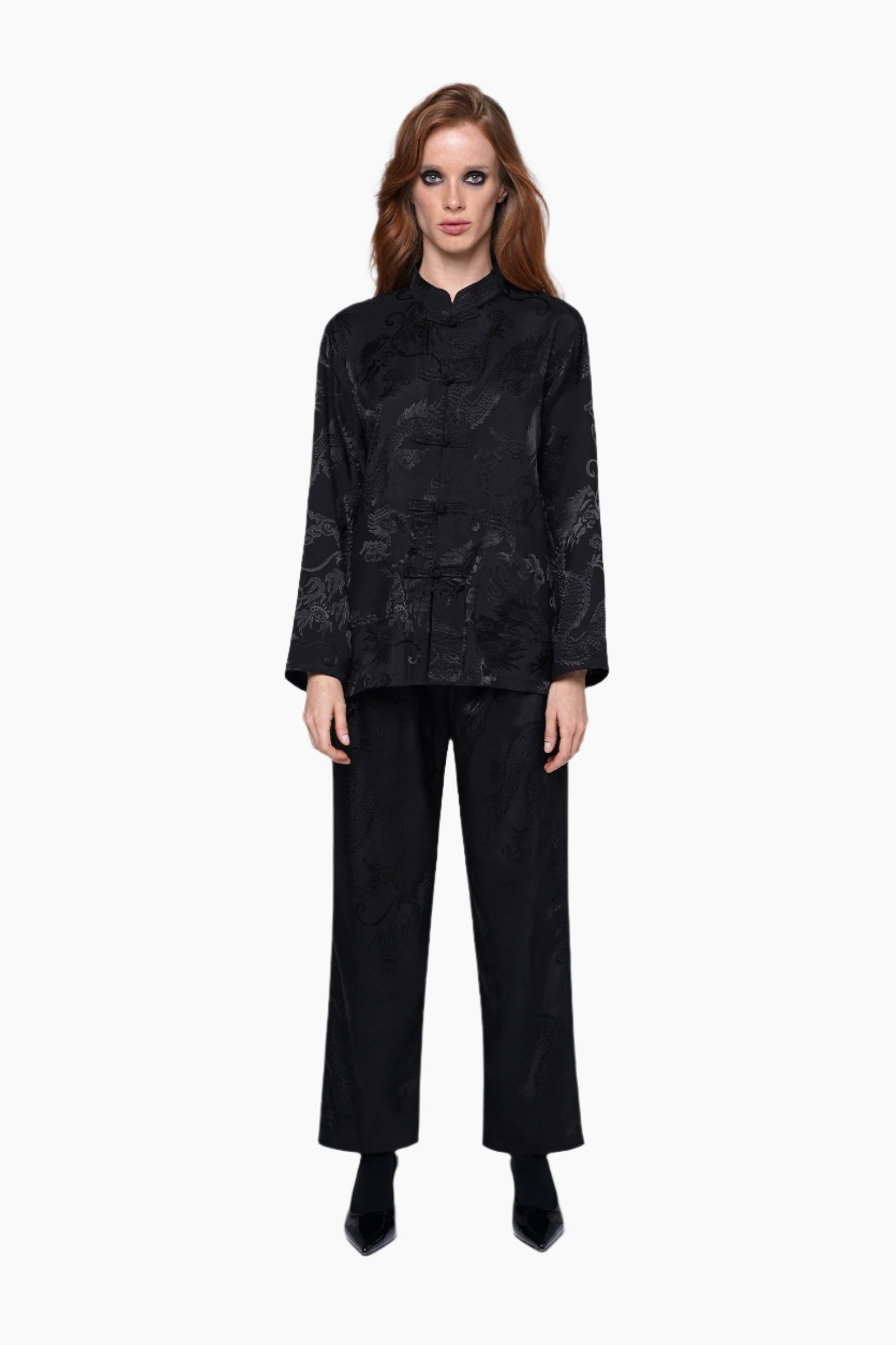 Woman wearing a black textured blouse and black pants on a white background