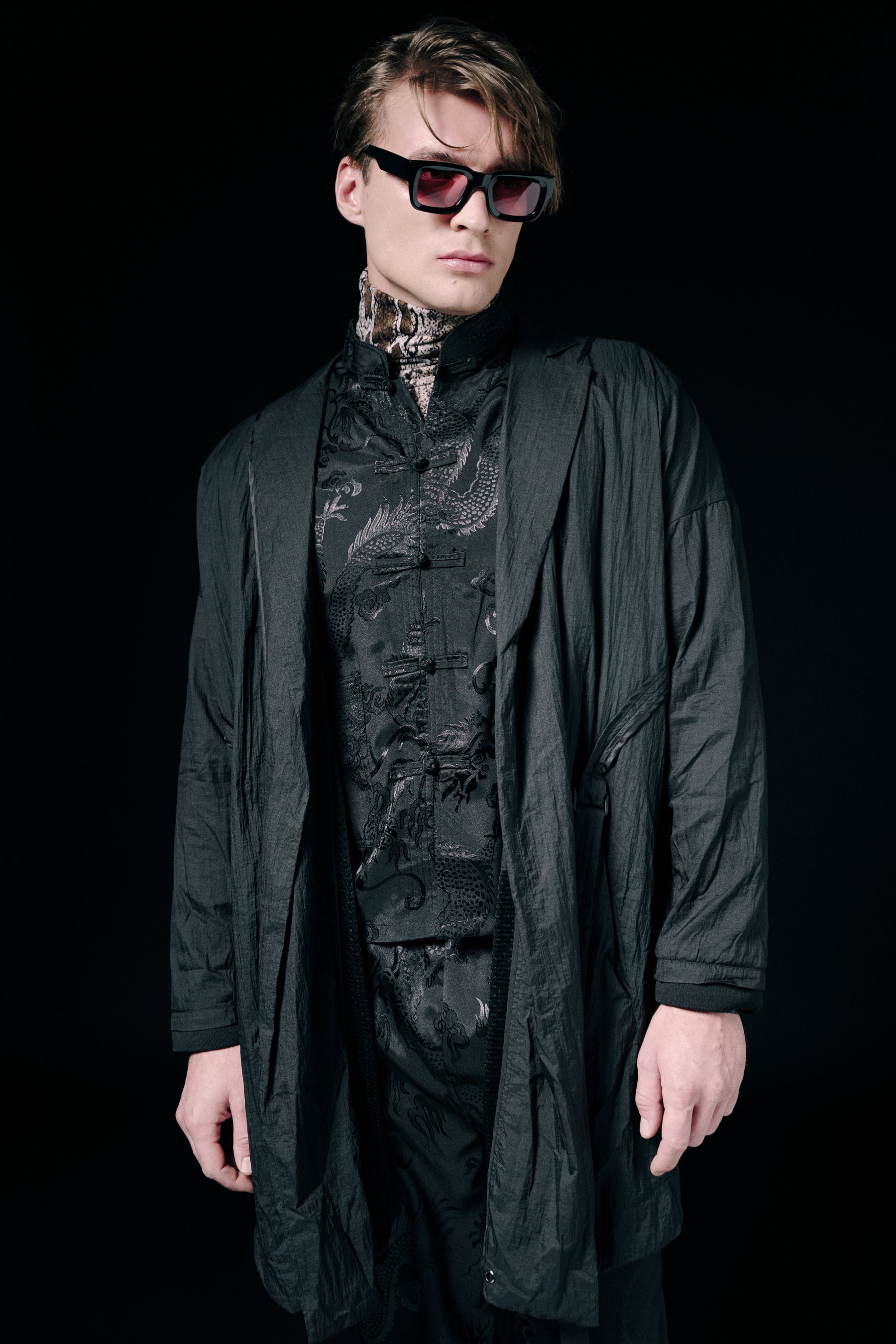 Man wearing a black patterned shirt and jacket