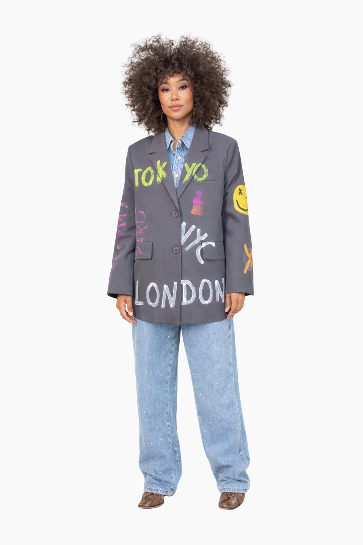 Person wearing a gray blazer with 'Tokyo', 'NYC', and 'London' text, standing against a white background.
