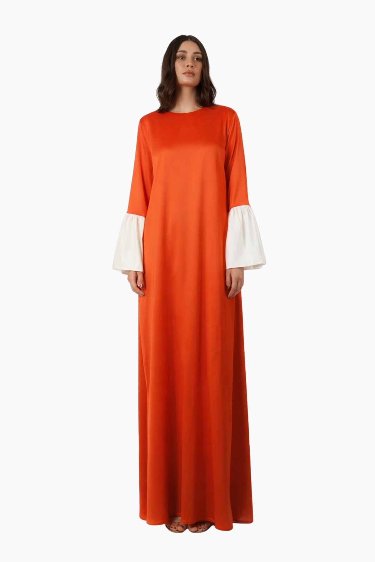 Woman wearing an orange long dress with white cuffs on a white background