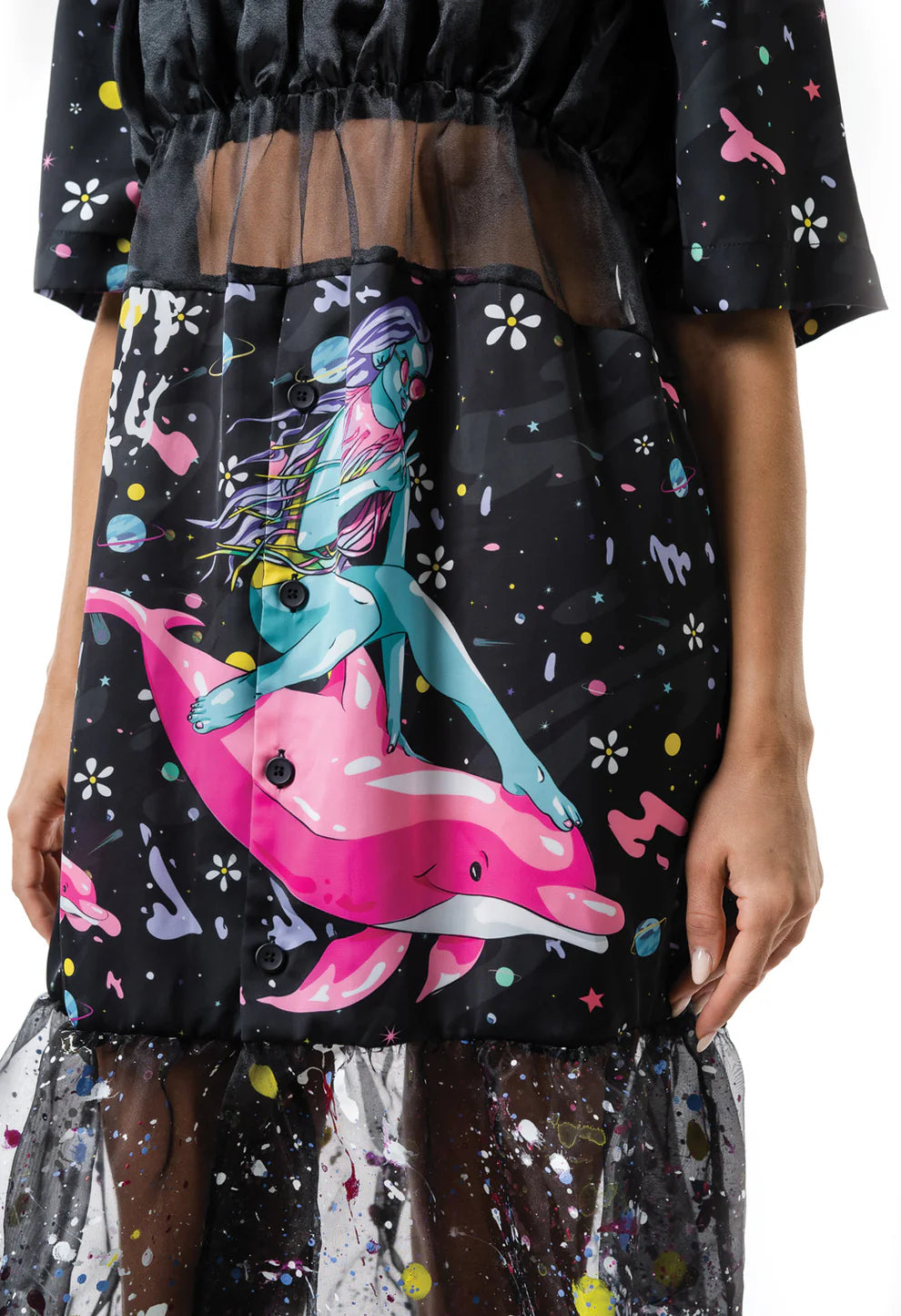 Woman wearing a black floral-patterned crop top and a skirt with sheer overlay on a white background
