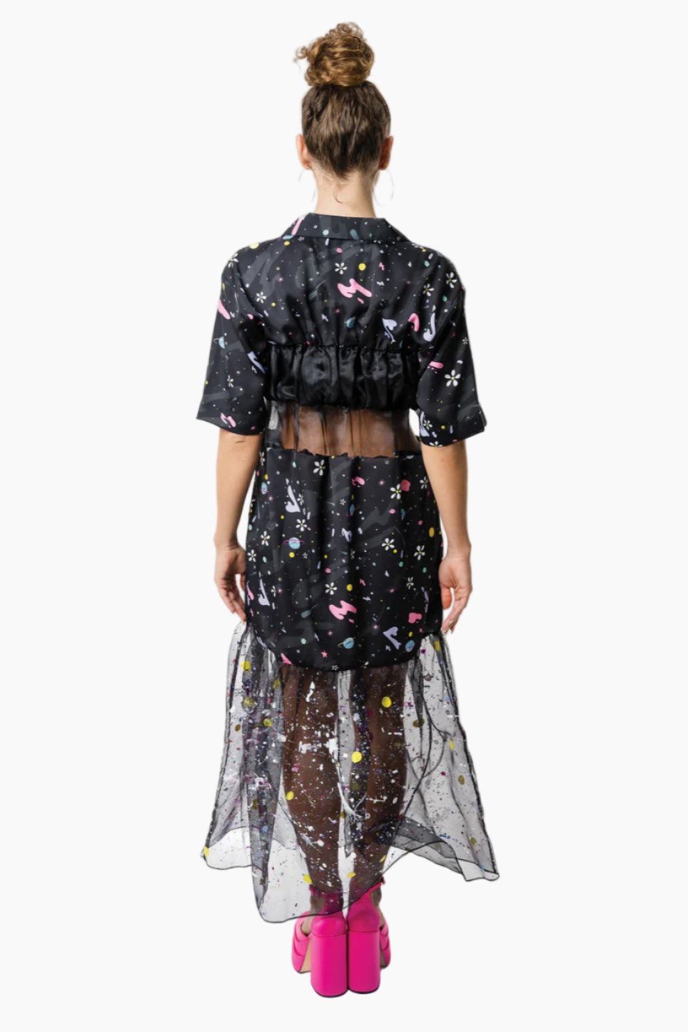 Woman wearing a black floral-patterned crop top and a skirt with sheer overlay on a white background