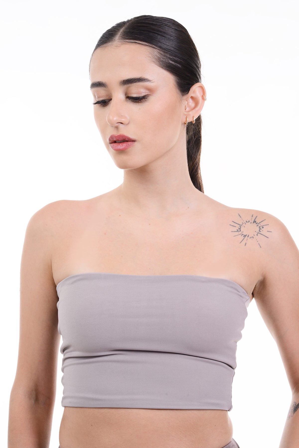 Woman wearing a strapless beige top against a white background