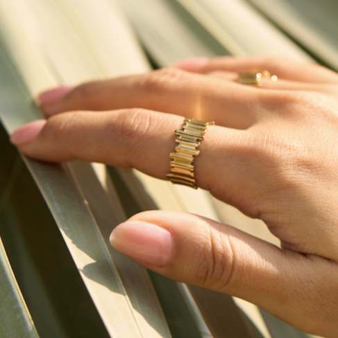 Hand wearing a gold ring with a blurred background