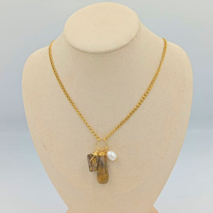 Gold necklace with a pendant on a mannequin bust against a light gray background