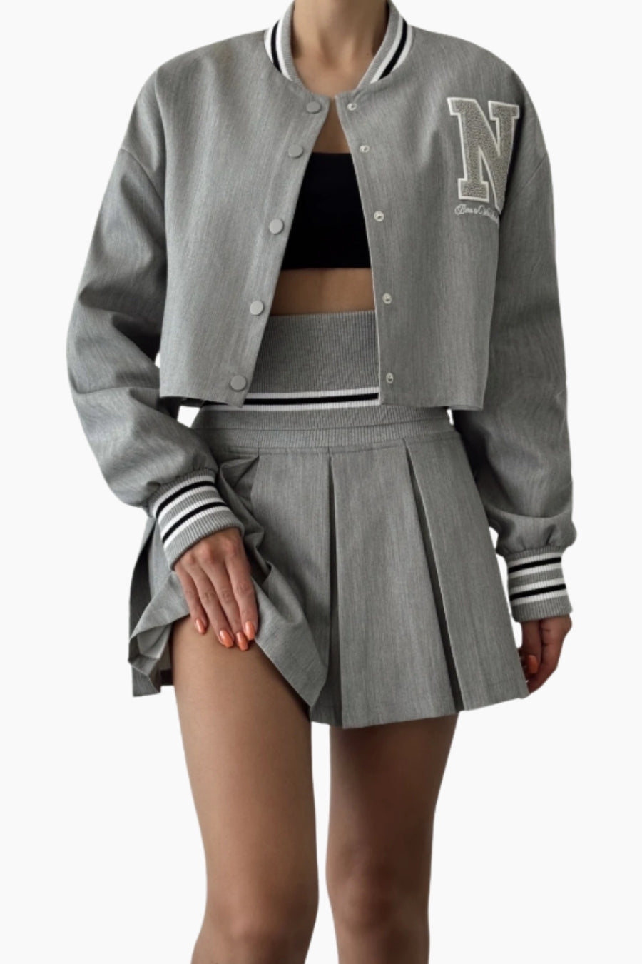 Gray varsity jacket with 'N' logo and pleated skirt