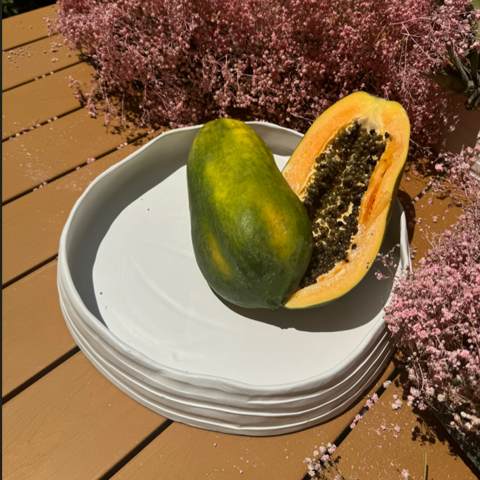 Papaya on a white plate with pink flowers in the background