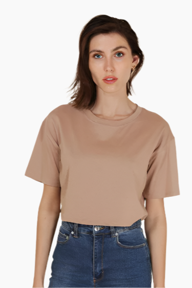 Woman wearing a beige t-shirt and blue jeans on a white background