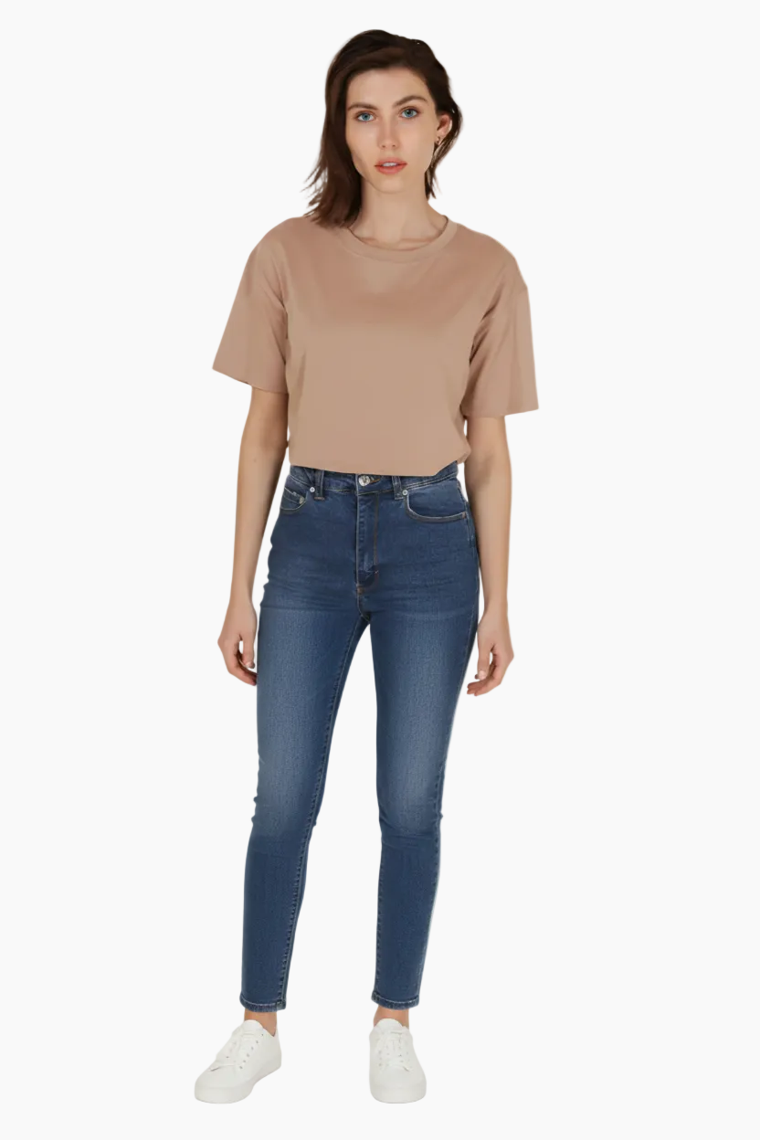 Woman wearing a beige t-shirt and blue jeans on a white background