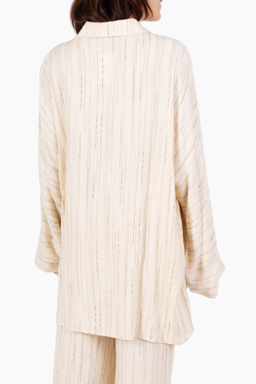 Person wearing a cream ribbed sweater and pants on a white background