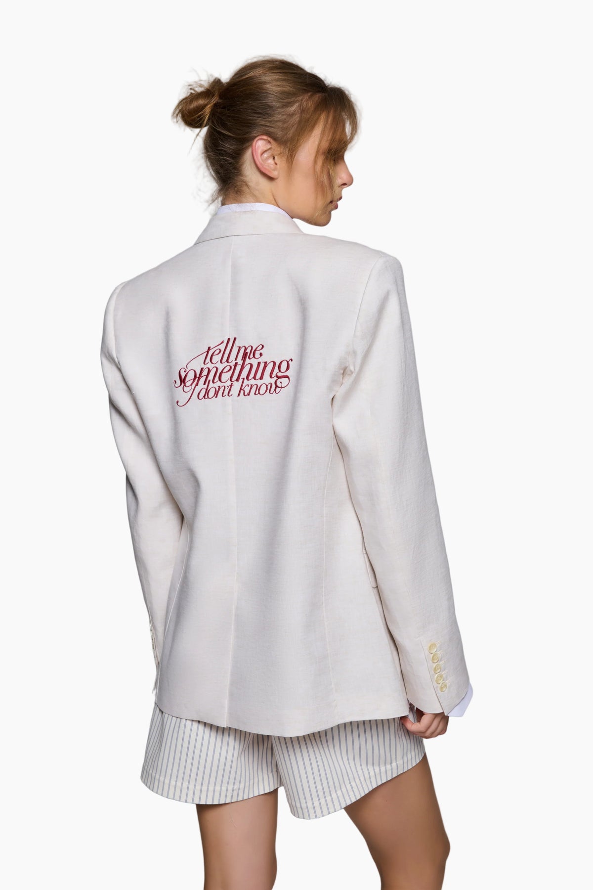 model wearing Italian oversized fit Cream White Lenin blazer made with love by the finest tailors.
Embedded with an embroidery "Tell me something İ don't know" on the upper back of the garment in a vivid burgundy color.