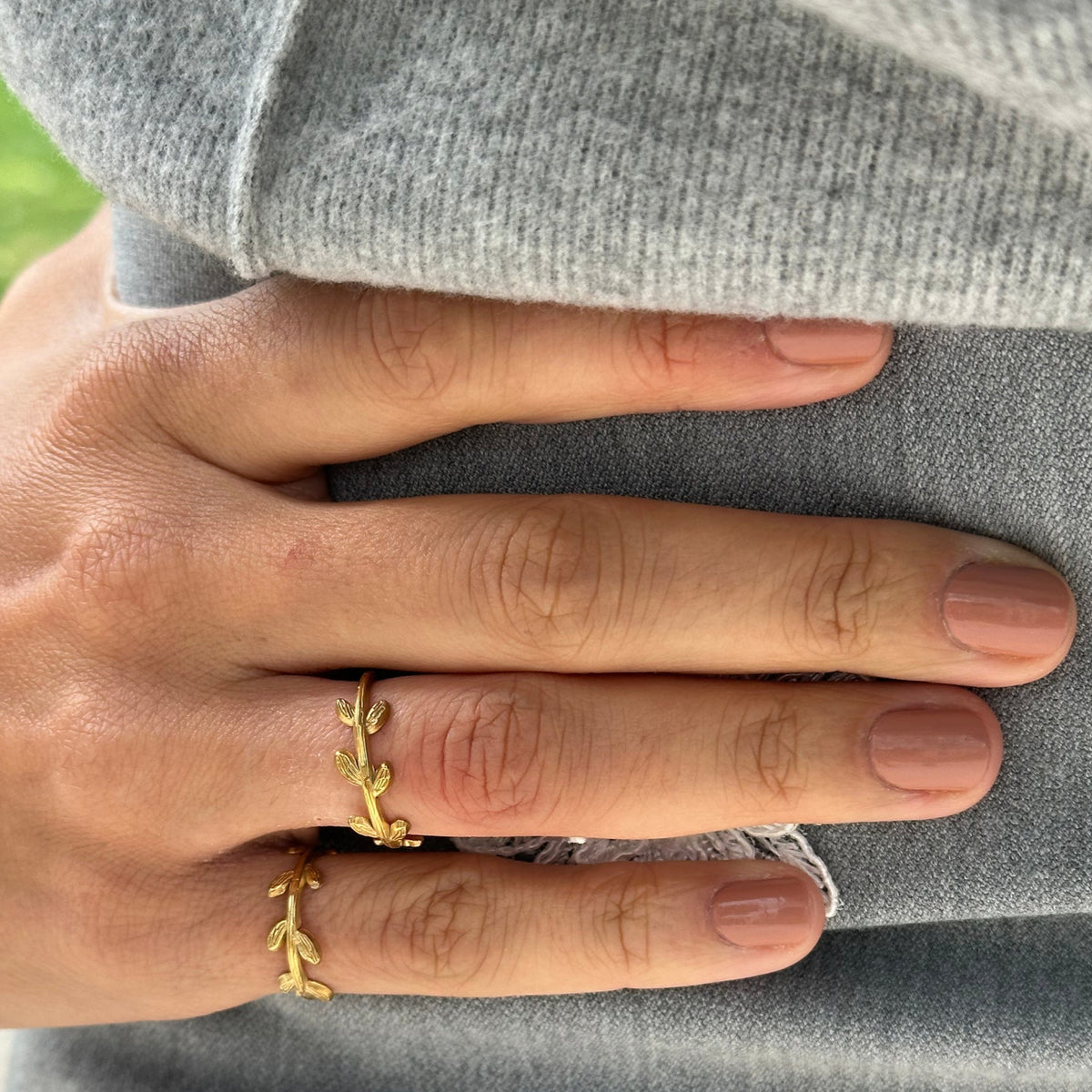 Hand wearing a gold ring with a blurred background