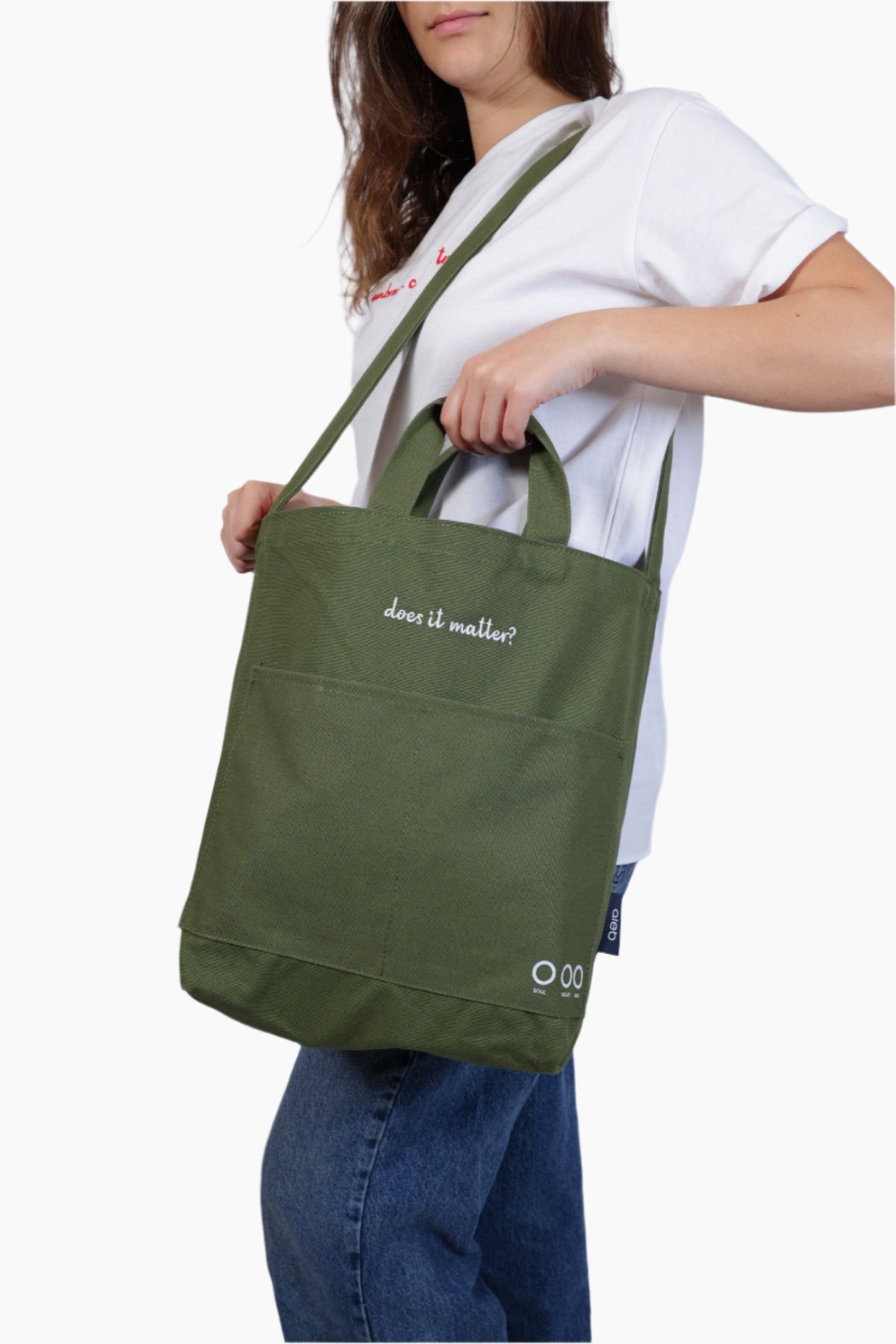 Person holding a green tote bag Person wearing a green bag "Does it matter" Unisex Bag, white shirt, and blue jeans.