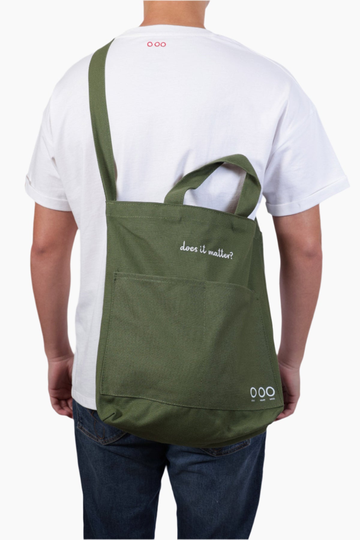 Person wearing a green bag "Does it matter" Unisex Bag, white shirt, and blue jeans.