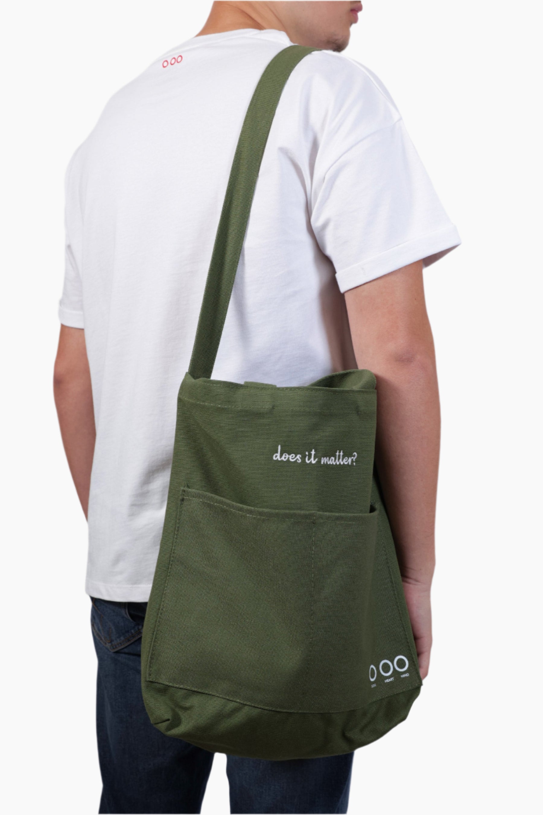 Person wearing a green bag Person wearing a green bag "Does it matter" Unisex Bag, white shirt, and blue jeans.