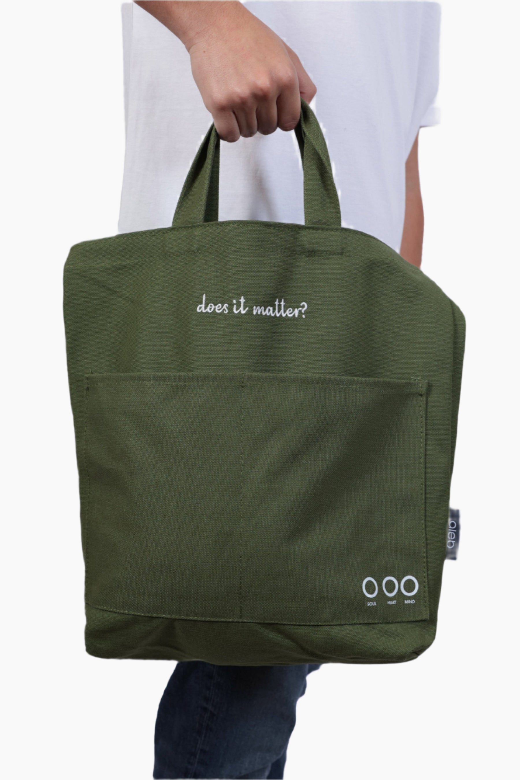 Green tote bag with 'does it matter?' text held by a person