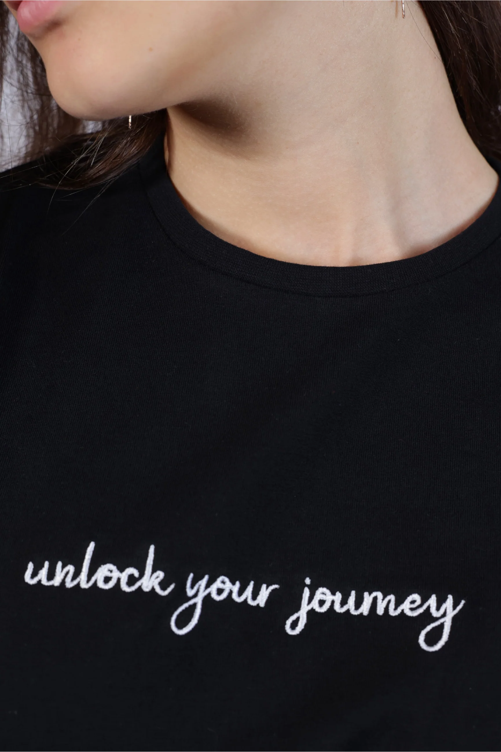 Person wearing a black t-shirt with 'unlock your journey' text , Unisex