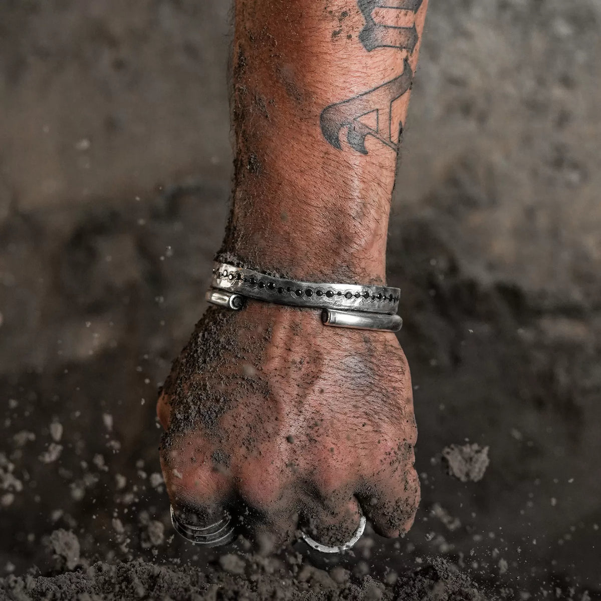 Hand with tattoos and bracelets in the sand