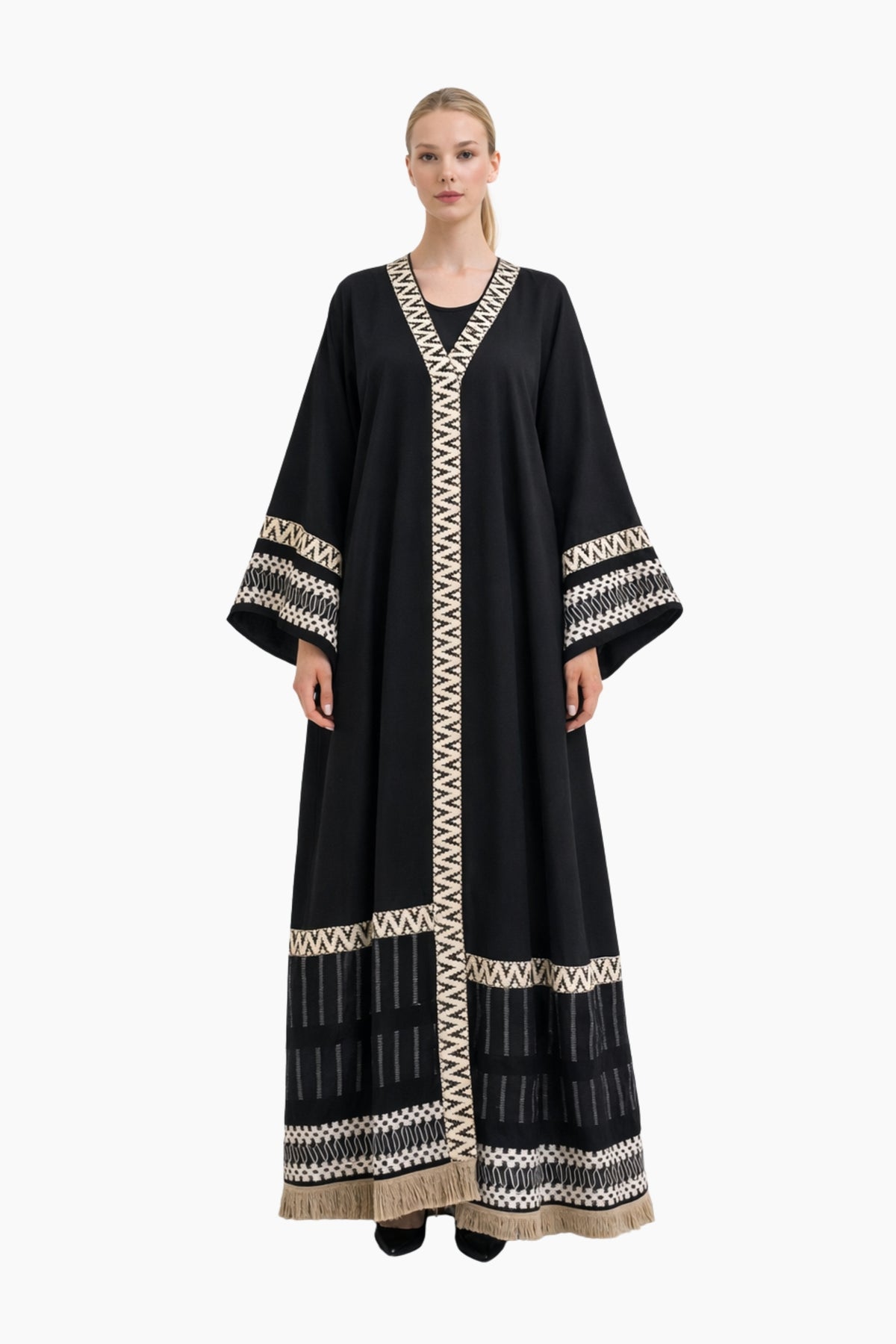Woman wearing a black abaya with white embroidery on a white background