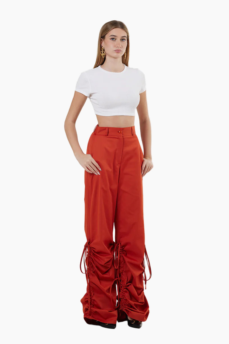 Woman wearing a white crop top and red high-waisted pants on a white background