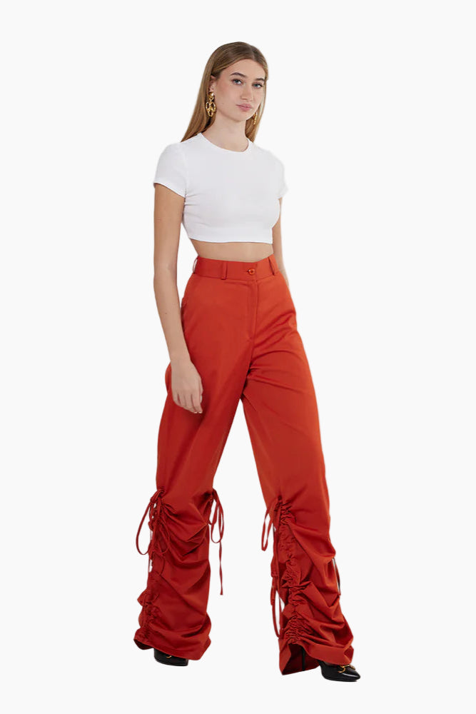 Woman wearing a white crop top and red ruffled pants on a white background