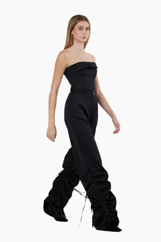 Woman wearing a black strapless jumpsuit on a white background