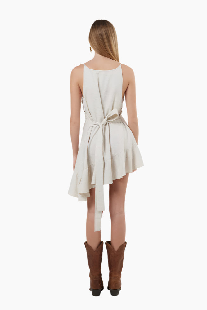 Woman wearing a white dress Strapped dress with asymmetrical ruffles on the hem, with brown boots
