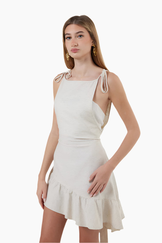 Woman wearing a white dress Strapped dress with asymmetrical ruffles on the hem, with brown boots