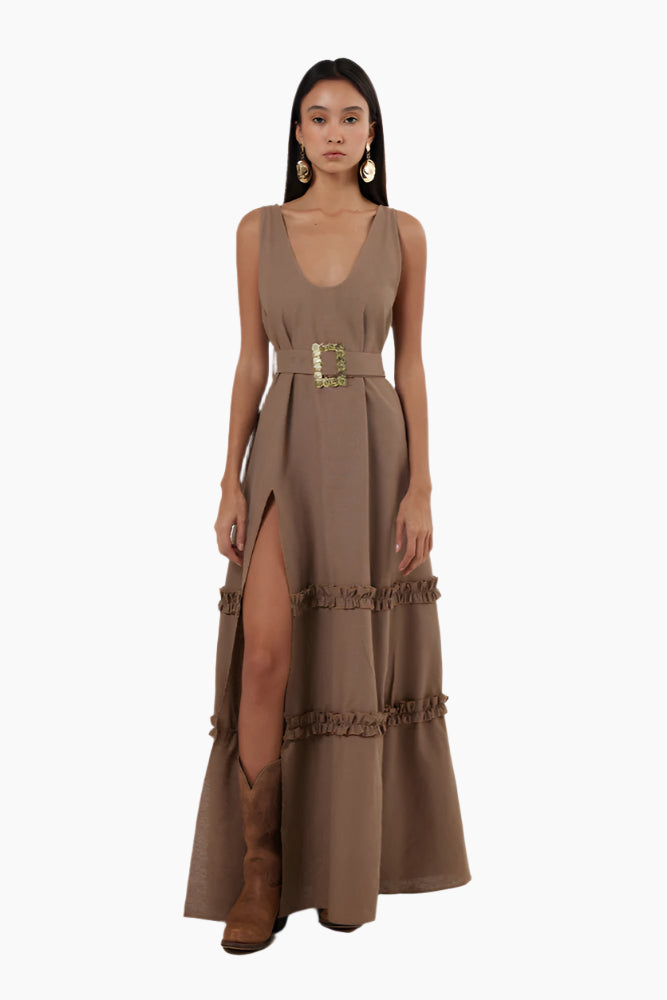 Woman wearing a brown dress with a belt . Floor-length dress with double ruffles, deep rounded neckline, belt, and a slit.